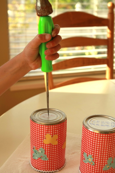 Punch a hole in the bottom of the can using a hammer and awl or nail. The hole must be large enough to put string through.