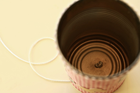 Insert a long piece of string through the hole in the can and tie a knot in the string on the inside of the can.