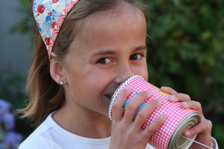 Little girl talking into the can phone - can you hear me?